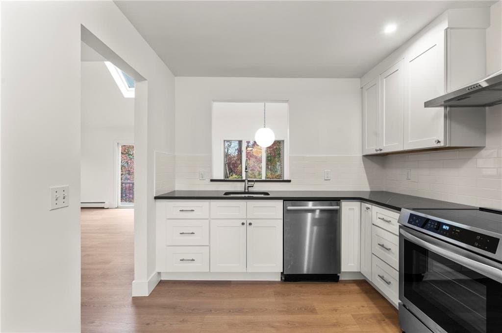 Eagle Bay Project — a renovated kitchen with white shaker cabinetry and honed black counters