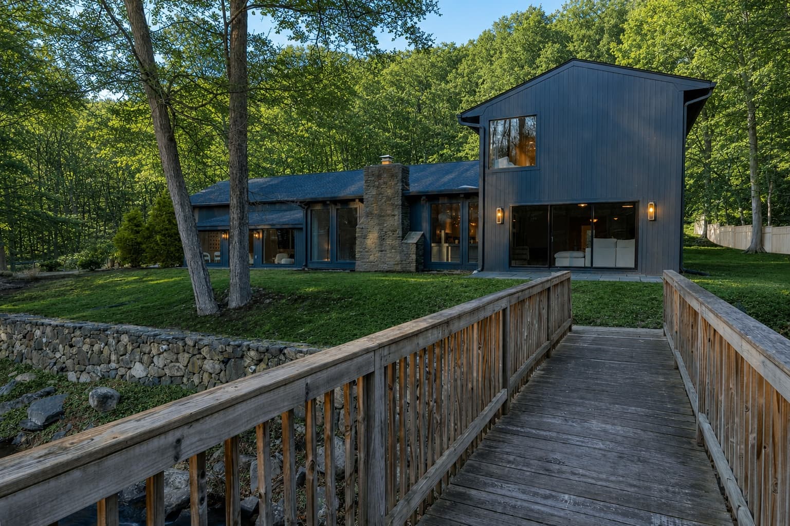 Hawley Project — a charcoal-clad contemporary home reached by a wooden footbridge over a creek
