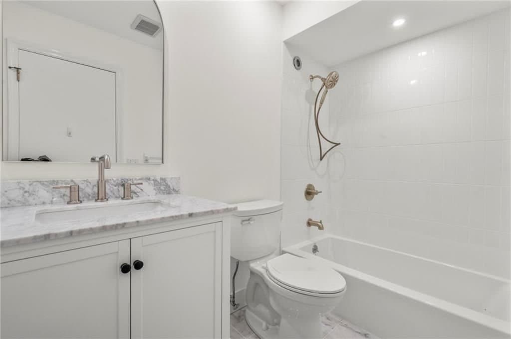 Eagle Bay bath — a Carrara marble vanity top with brushed fixtures beside a tiled tub and shower