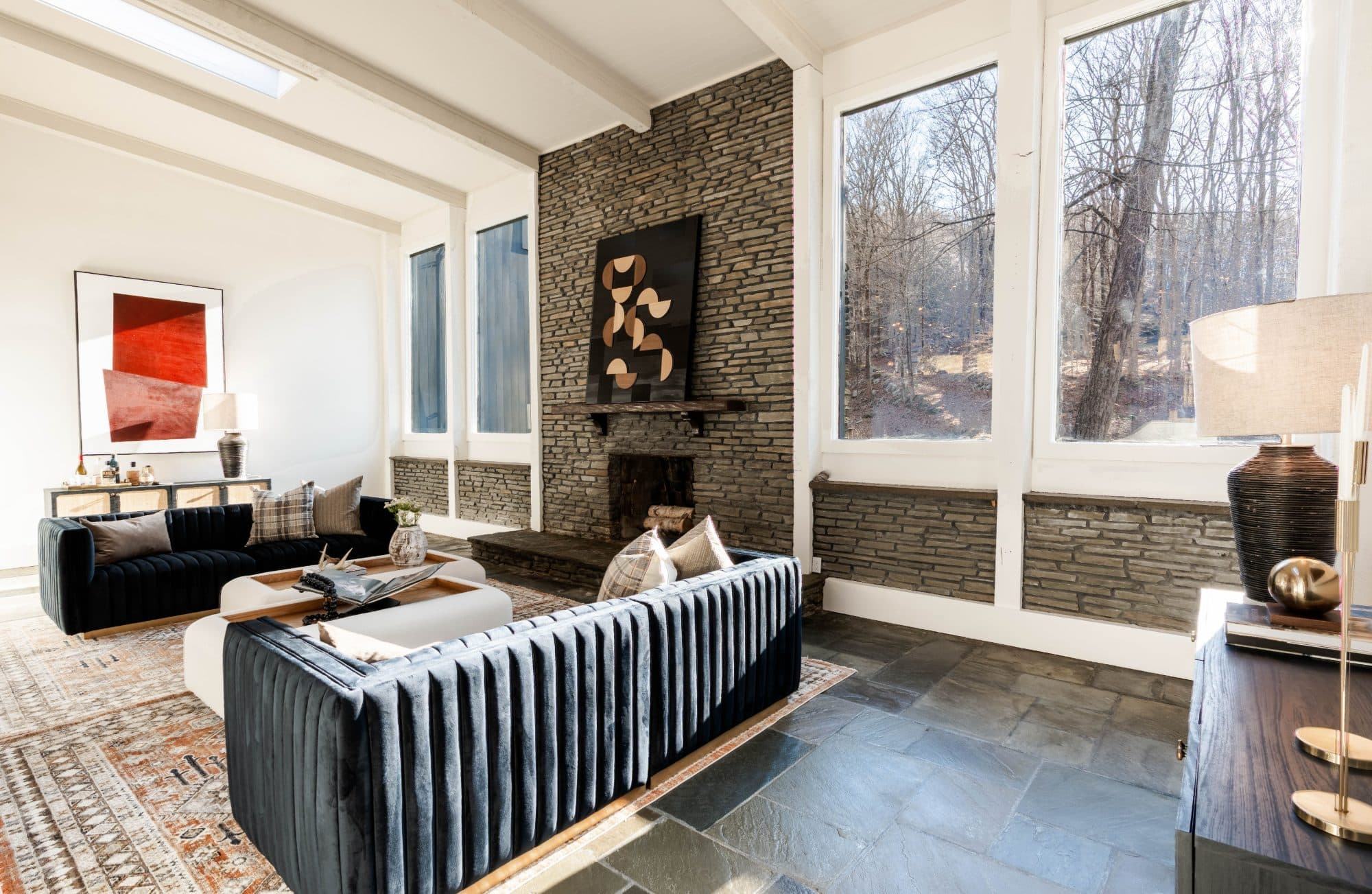 Hawley living room — stone hearth wall, velvet sofas, and a skylight above