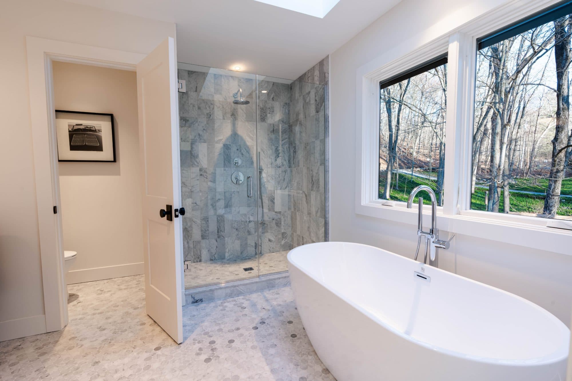 Hawley primary bath — freestanding tub beneath windows and a marble shower