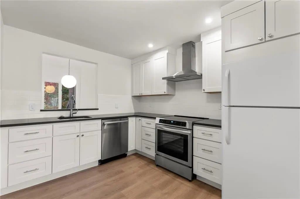 Eagle Bay after — the same corner rebuilt with white shaker cabinetry, black counters, and stainless appliances