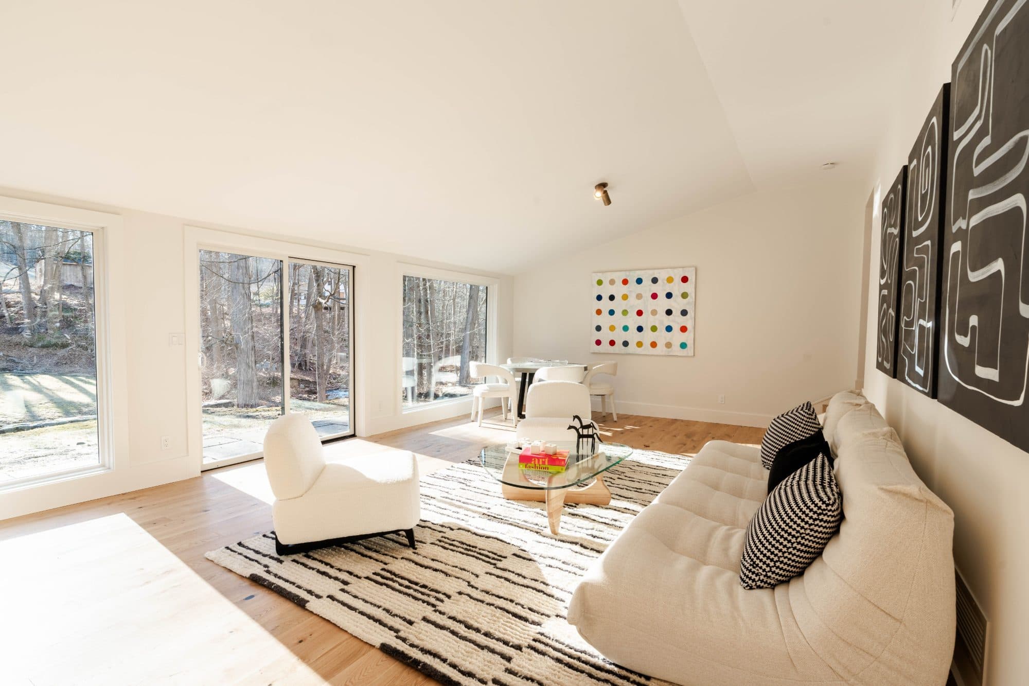 Hawley after — the rebuilt living space with vaulted ceiling, wall of glass to the creek, and art wall